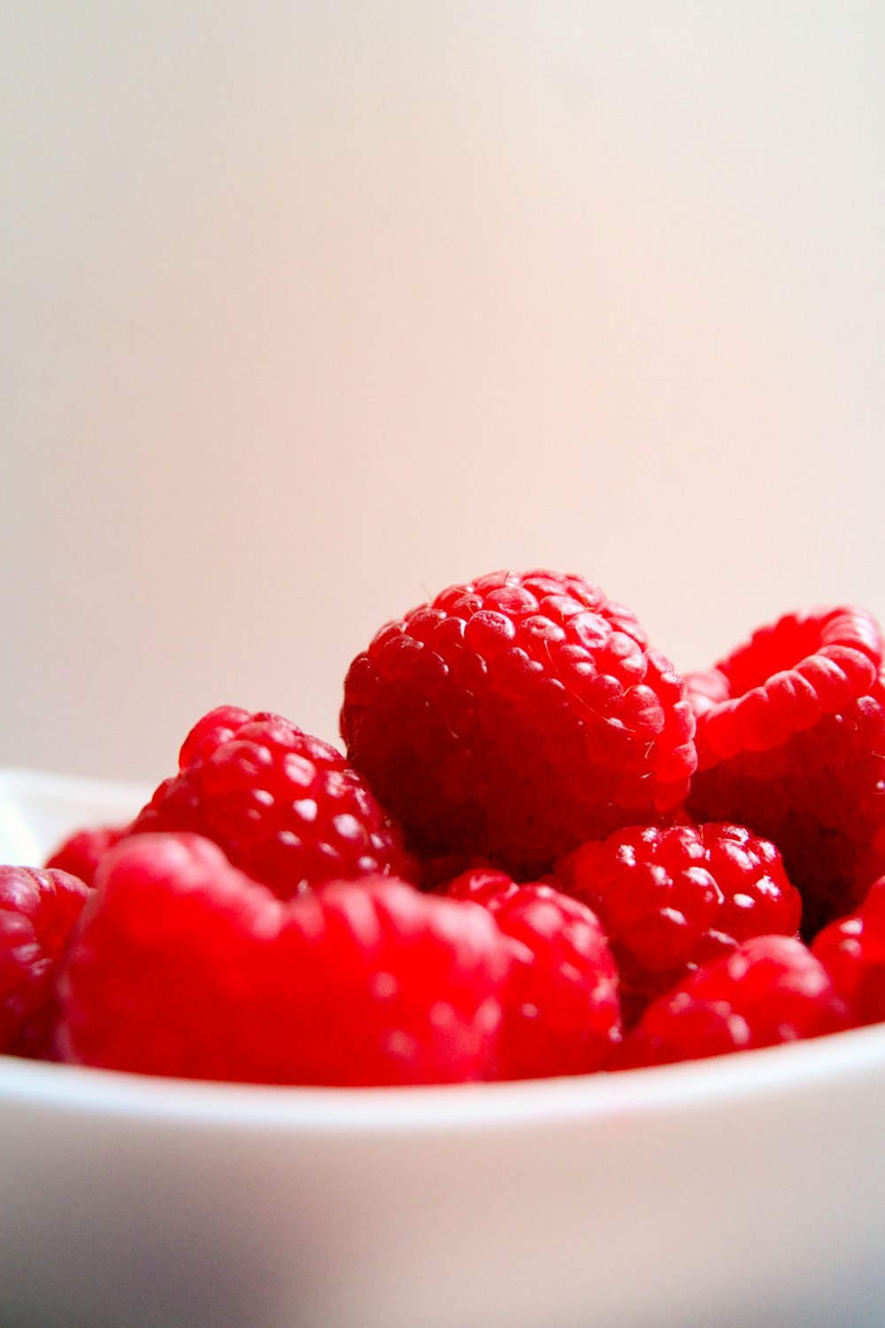 red raspberries on white ceramic bowl