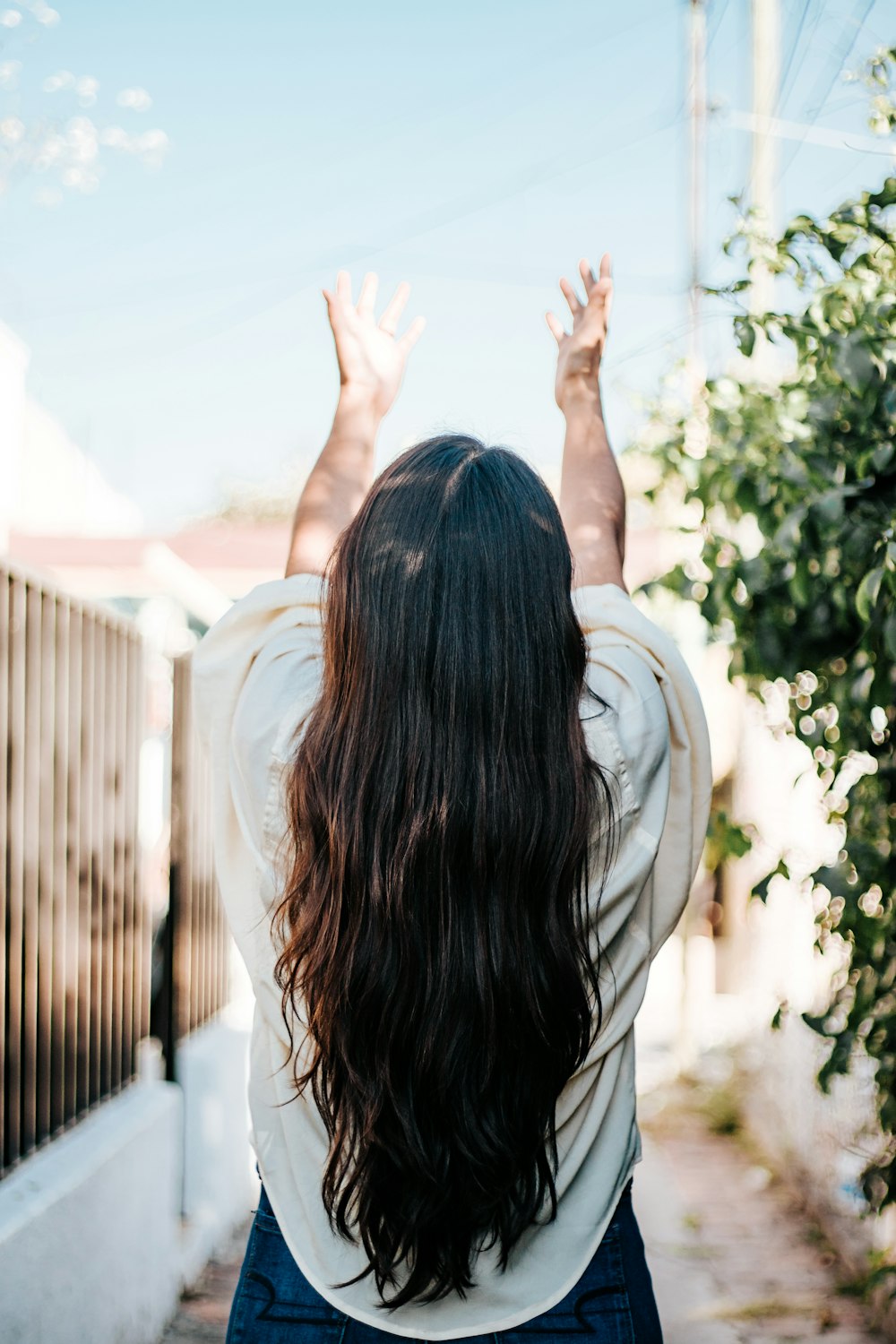 woman in white shirt standing near green tree during daytime