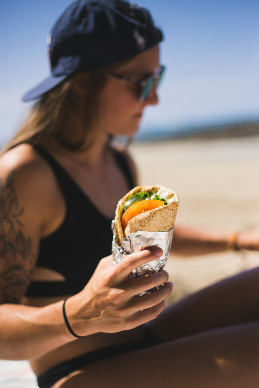 woman in black tank top eating burger