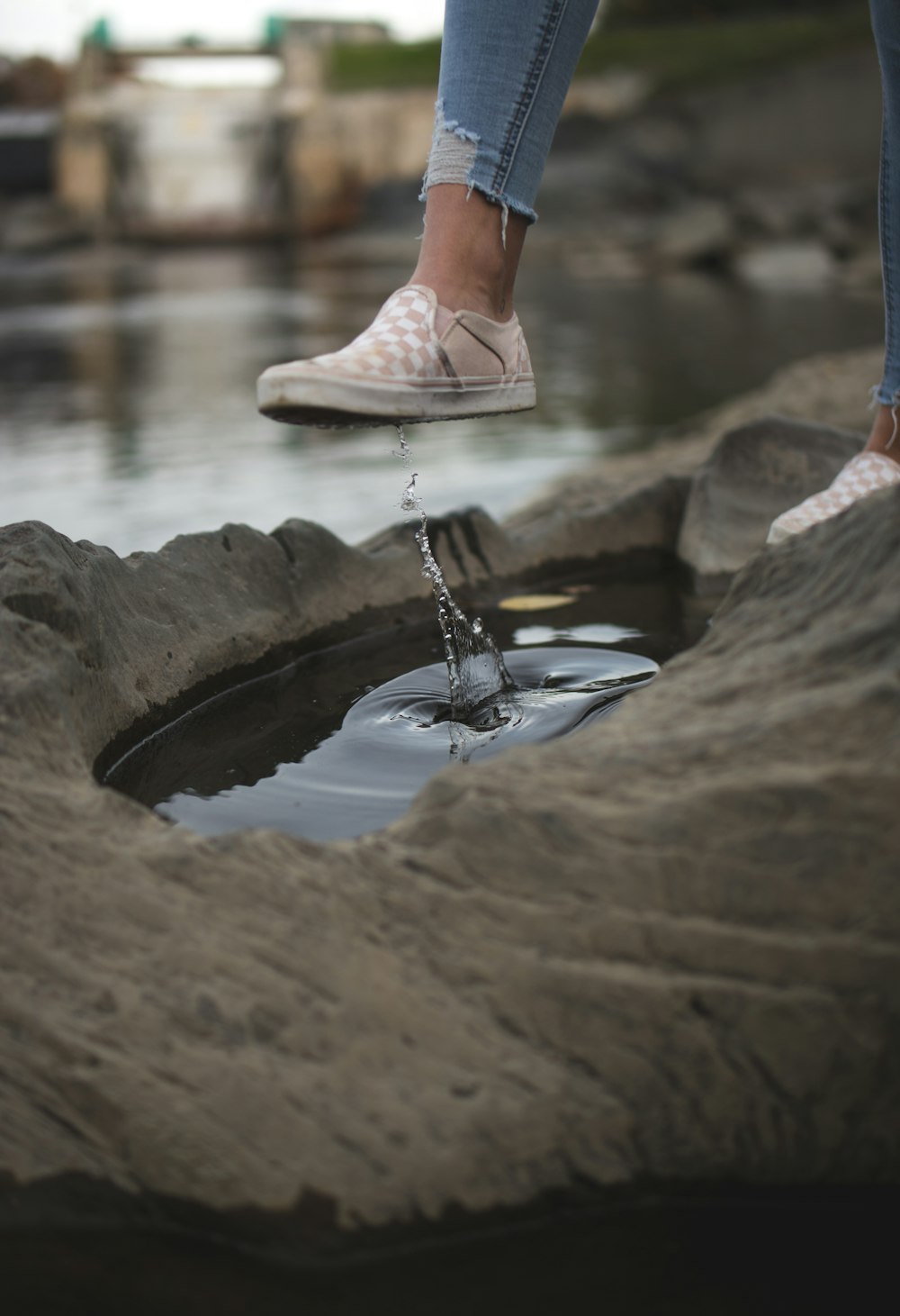 woman in brown leather sandals sitting on rock in front of water fountain