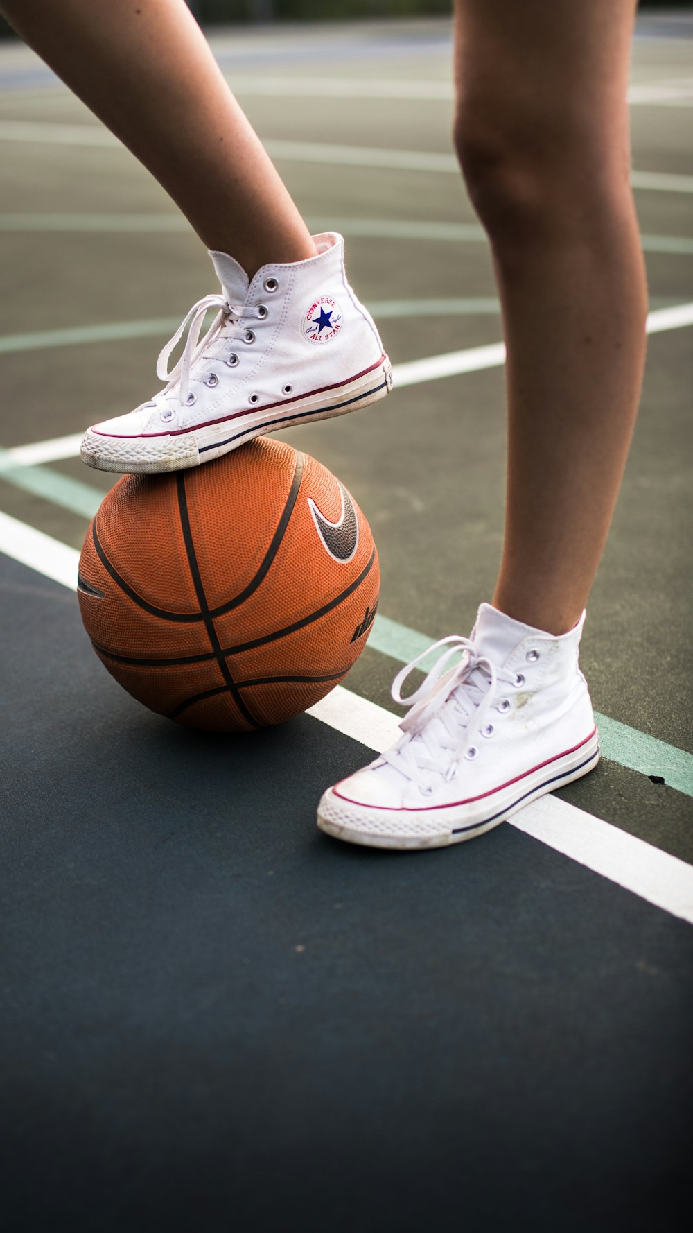pessoa em sapatos de basquete nike brancos em pé na quadra de basquete