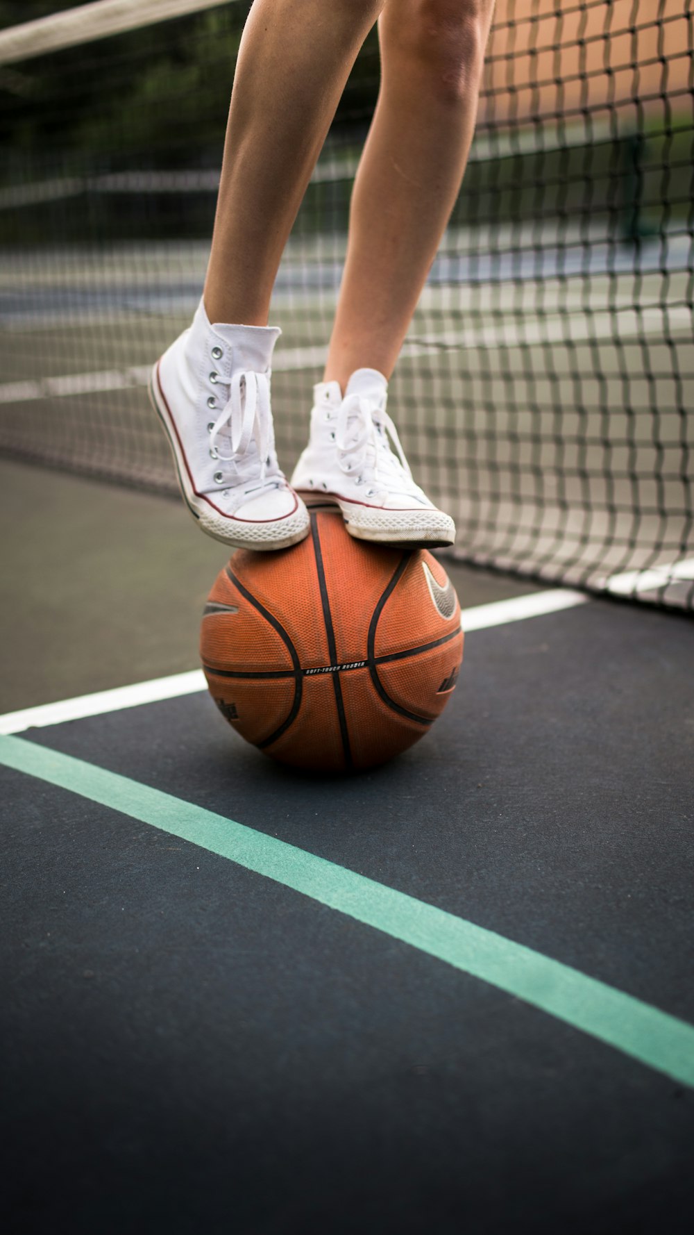 person in white nike athletic shoes standing on basketball court
