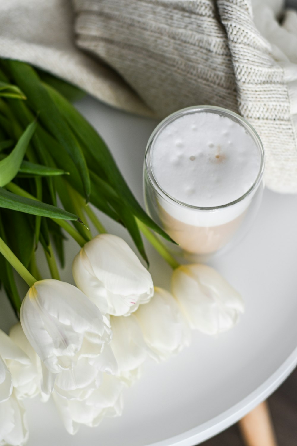 a white plate topped with white flowers next to a jar of cream