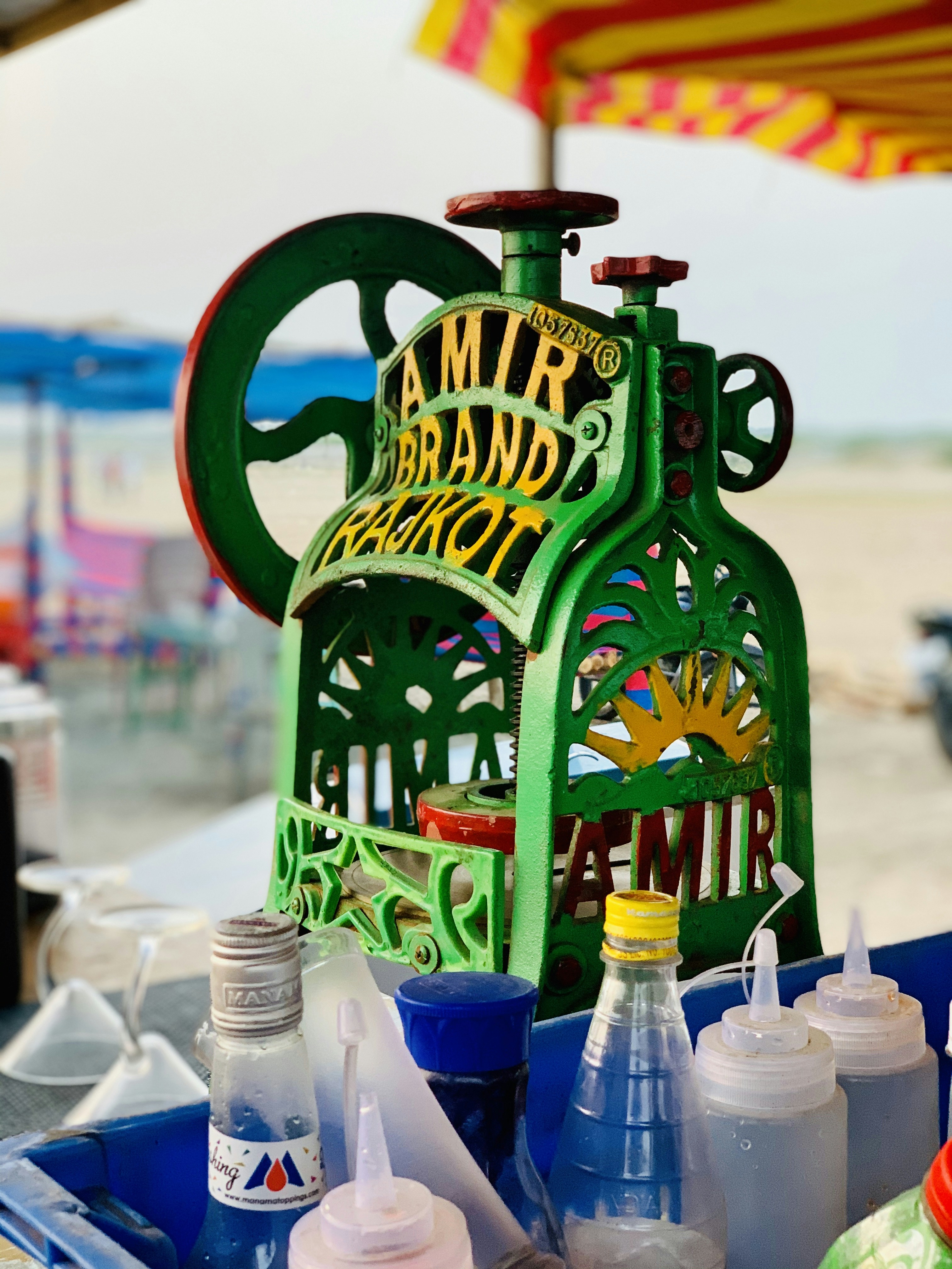 Colorful snow cones sitting next to an ice crusher machine