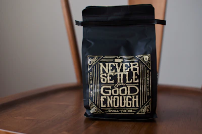 Close-up of a matte black coffee bag with golden details, set against a backdrop of handcrafted Mexican textiles.