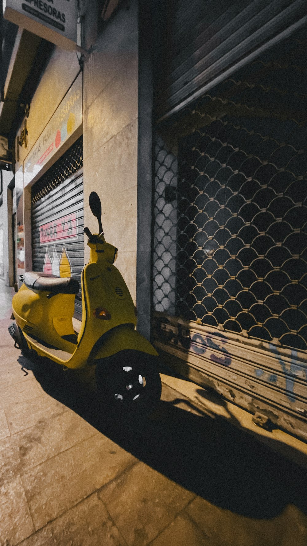 yellow motor scooter parked beside brick wall