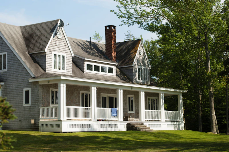 Older two-story home with white trim framed by trees