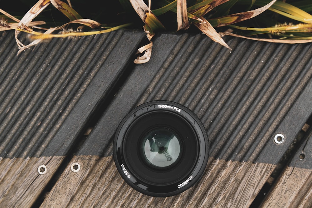 Schwarzes Kameraobjektiv auf grauem Holztisch