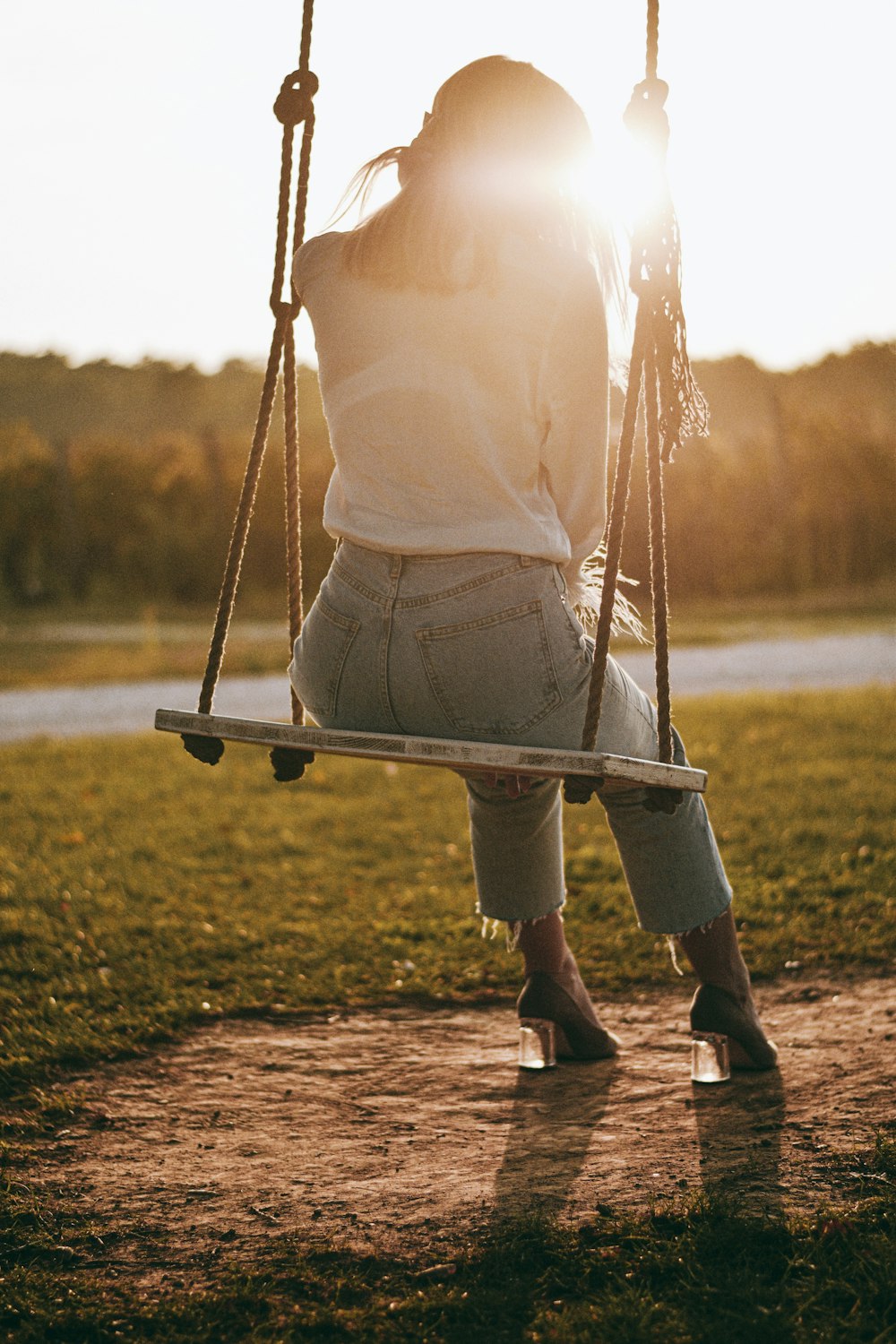 woman in white long sleeve shirt sitting on swing during daytime