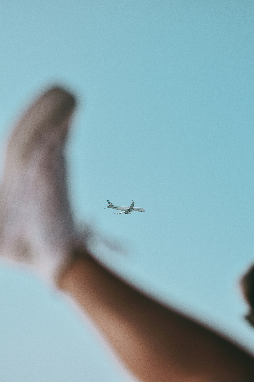 person in white long sleeve shirt with airplane in the sky during daytime