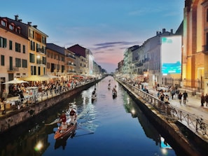 people riding on boat on river between buildings during daytime