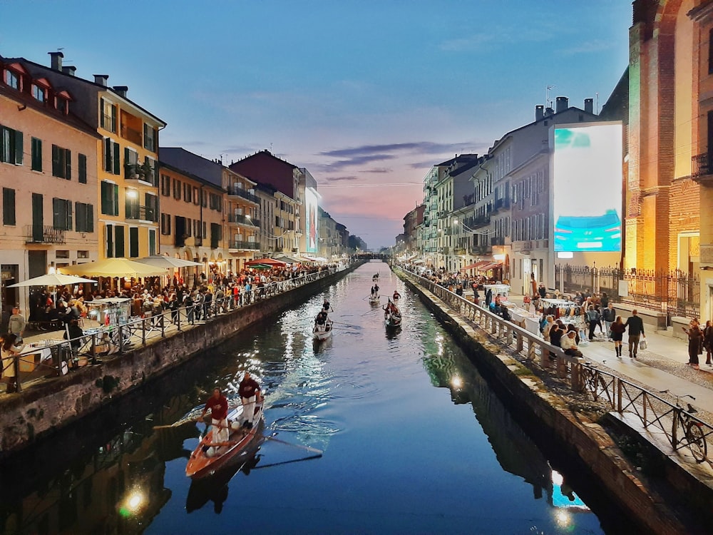 people riding on boat on river between buildings during daytime