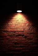 A textured brick wall with soft ochre lighting, evoking a warm and serious atmosphere.