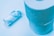 Two rolls of toilet paper are displayed on a light blue background. One roll is standing upright, while the other is lying horizontally and appears to be partially used. The paper texture and embossed patterns are visible due to the lighting.