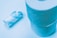 Two rolls of toilet paper are displayed on a light blue background. One roll is standing upright, while the other is lying horizontally and appears to be partially used. The paper texture and embossed patterns are visible due to the lighting.