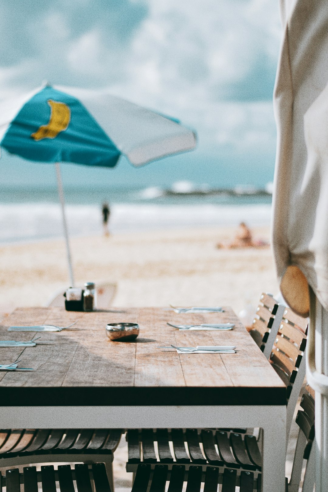 person sitting on brown wooden chair near beach during daytime