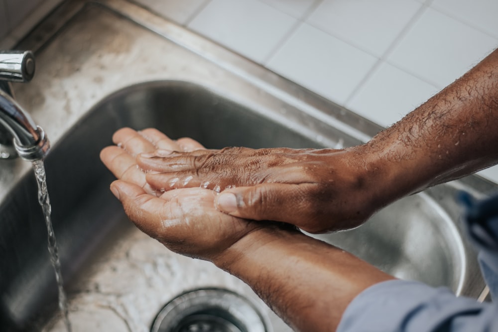eine Person, die sich die Hände in einem Waschbecken wäscht