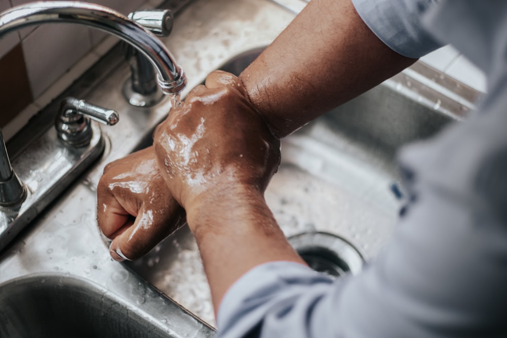 Persona con camiseta gris lavándose las manos
