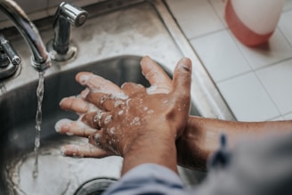 person in white shirt washing hands