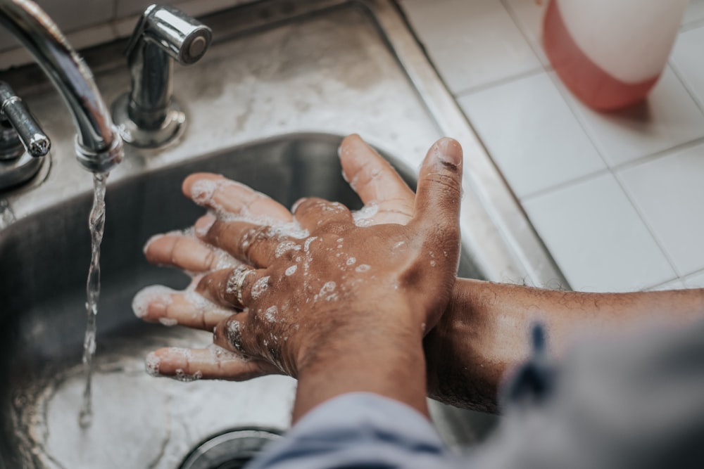 person in white shirt washing hands
