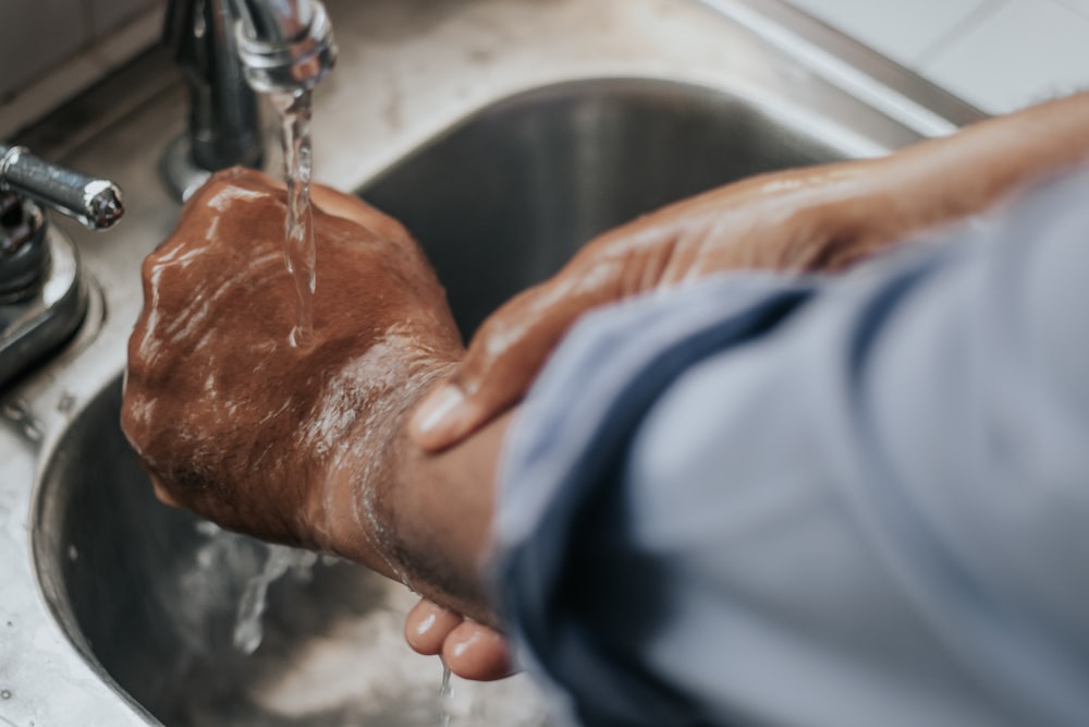 person in blue and white jacket holding silver faucet