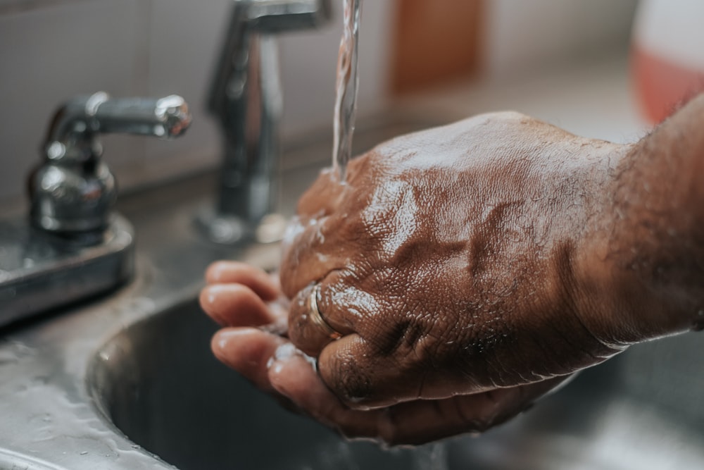 person washing hands on sink