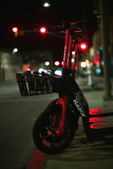A vibrant electric scooter parked against a neon-lit city backdrop.