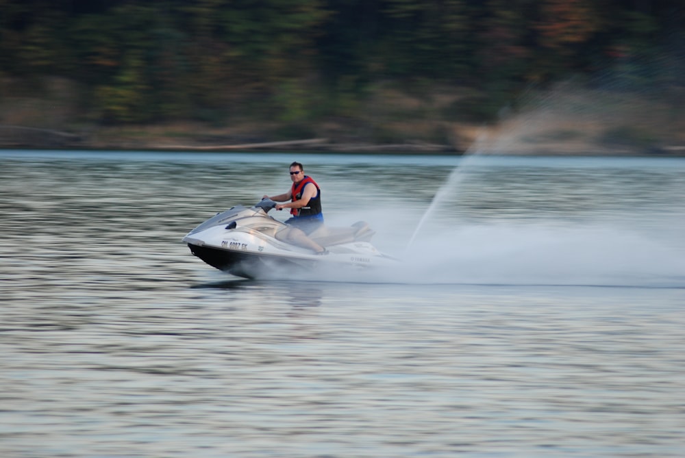 man riding white personal watercraft on body of water during daytime