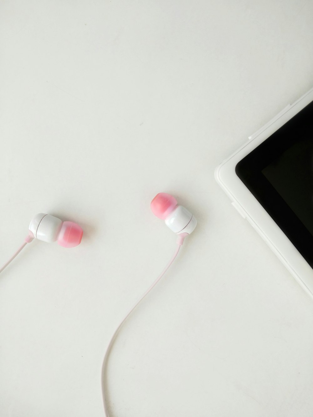 white and red earbuds on white table