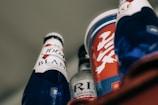 Several beverage containers with diverse labels and designs are arranged, featuring blue and red colors prominently. One bottle has 'Blanc 1664' written on it, and others include a mix of text and abstract designs.