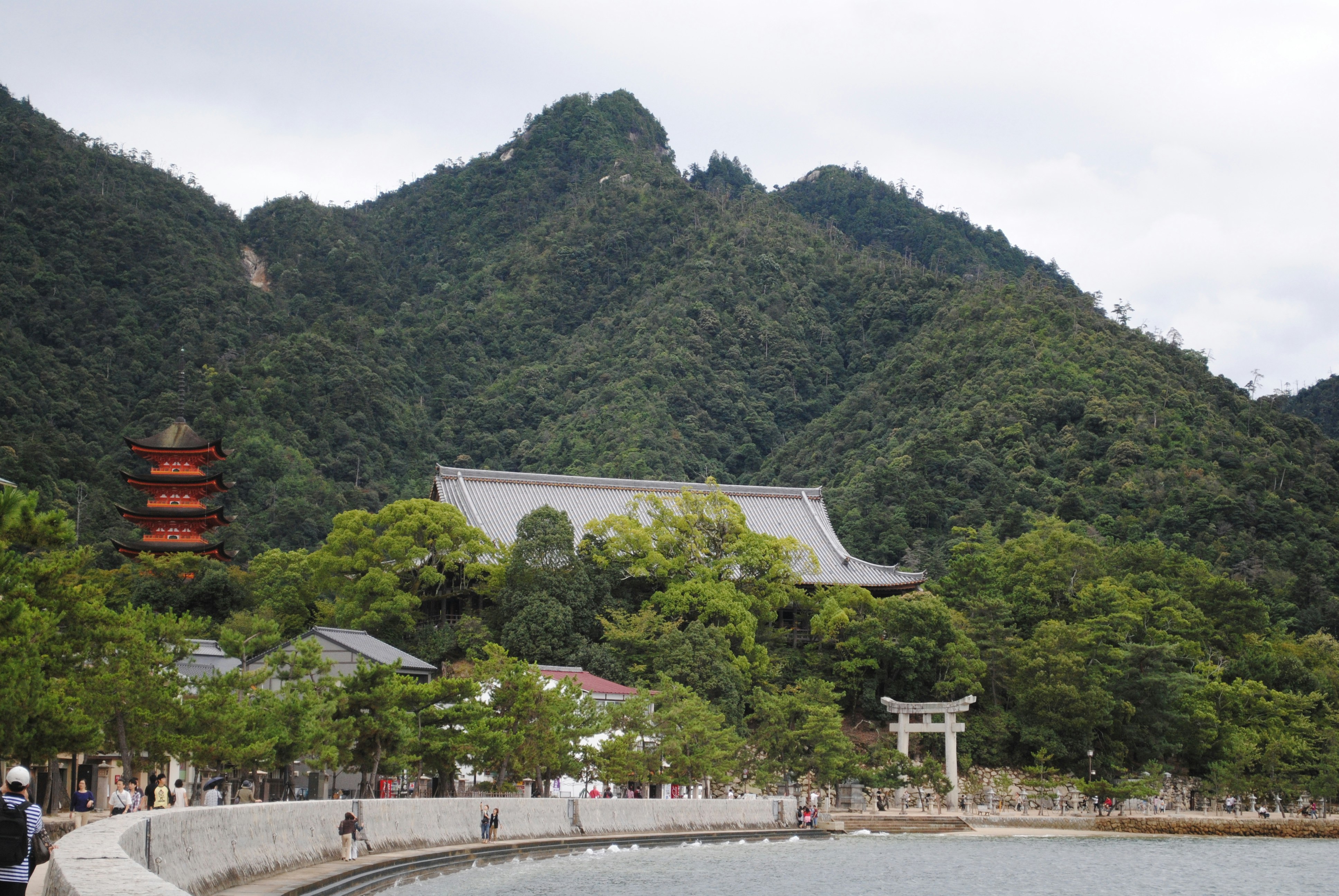 people walking on sidewalk near mountain during daytime