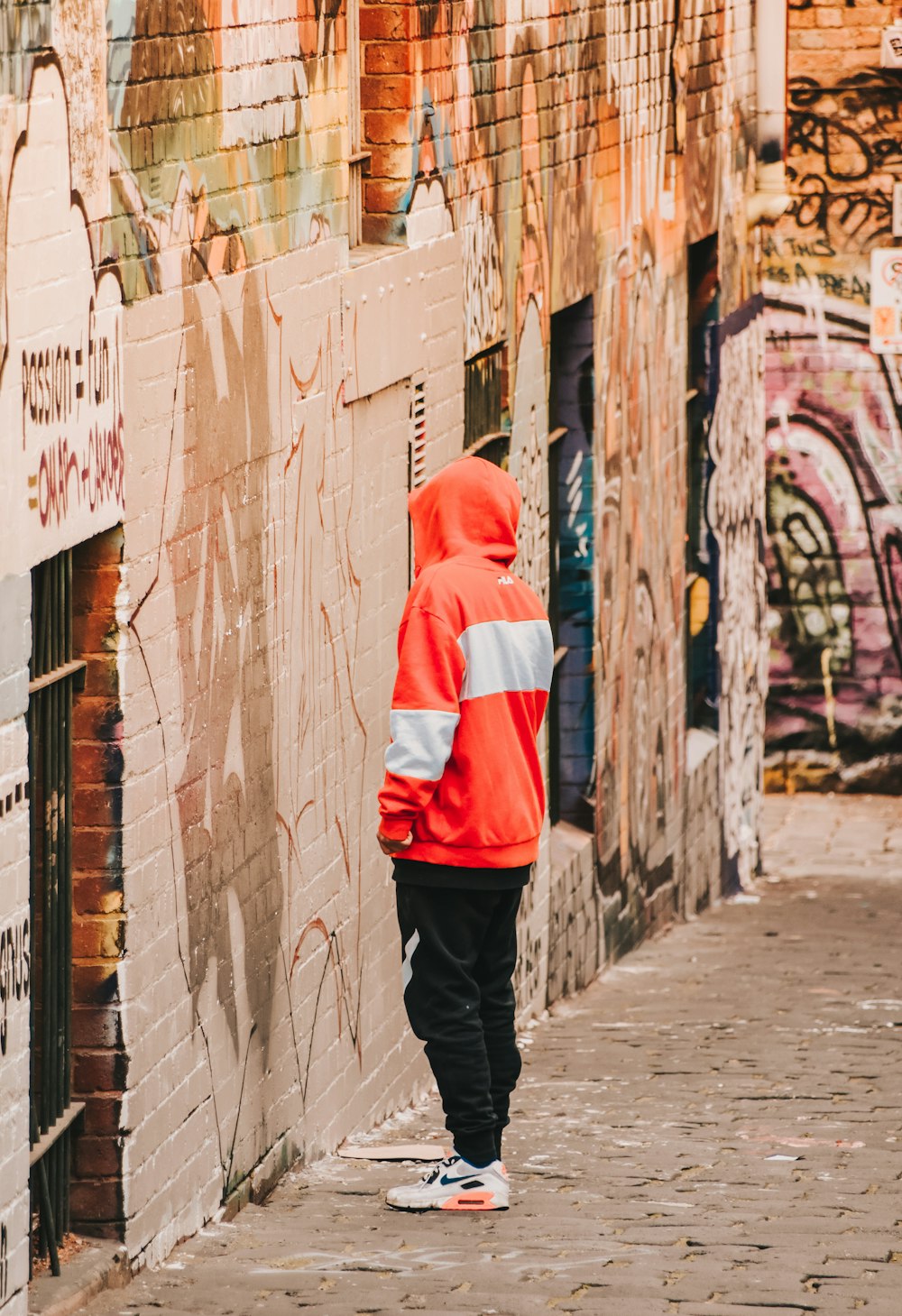 person in red and white hoodie standing on gray concrete floor during daytime