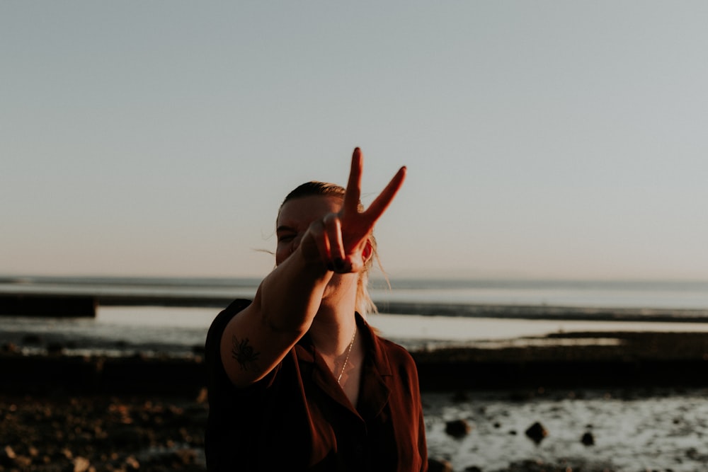 woman in black jacket standing on beach during sunset