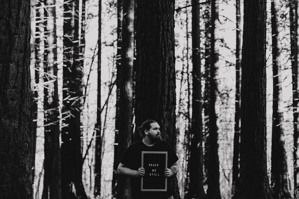 Hombre en camiseta negra de cuello redondo de pie en el bosque