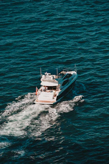 Aerial shot of a luxury yacht cutting through deep navy waters with white foam trail
