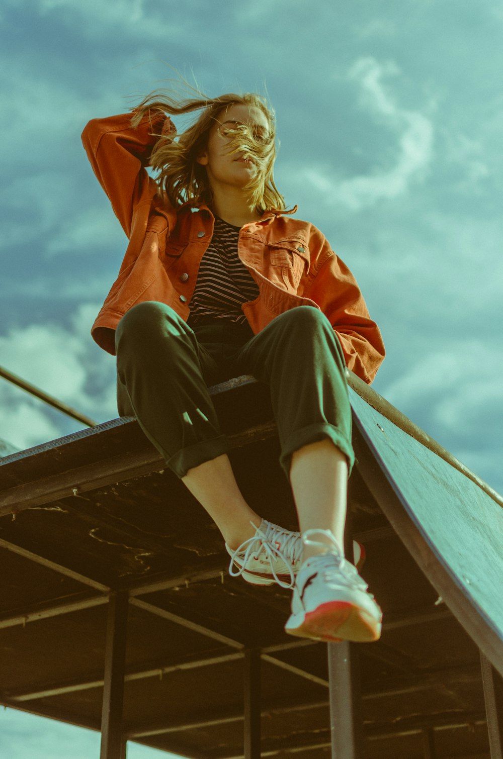 woman in red jacket sitting on brown wooden boat during daytime