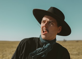 man in black jacket wearing blue and white scarf and black hat