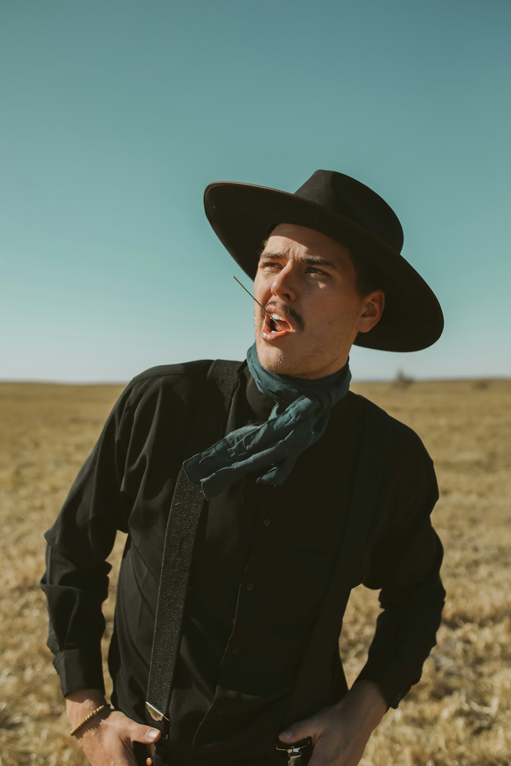 hombre con chaqueta negra con bufanda azul y blanca y sombrero negro