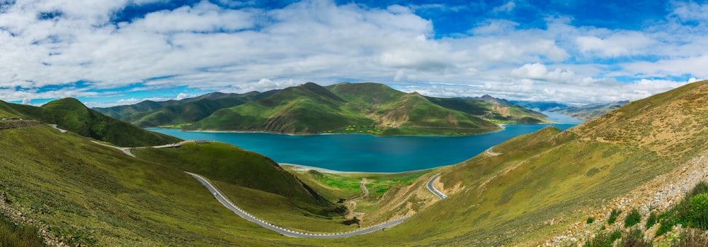 green mountains near body of water under blue sky during daytime