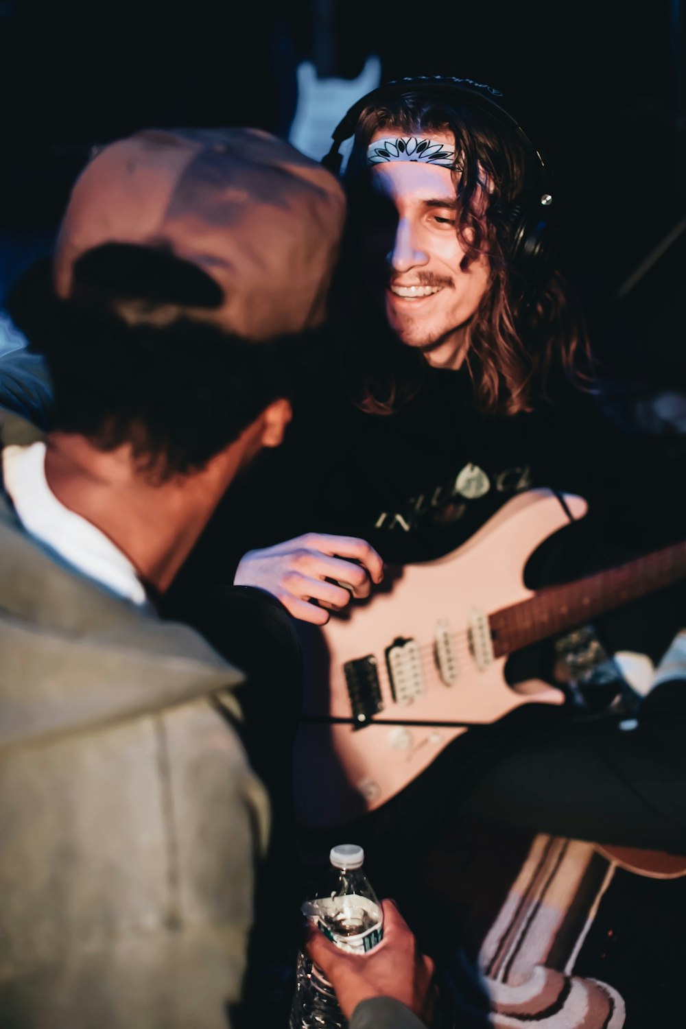 man in gray suit jacket holding white electric guitar