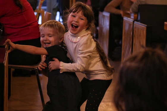 Children happily playing together in a bright, colorful classroom with attentive caregivers nearby.