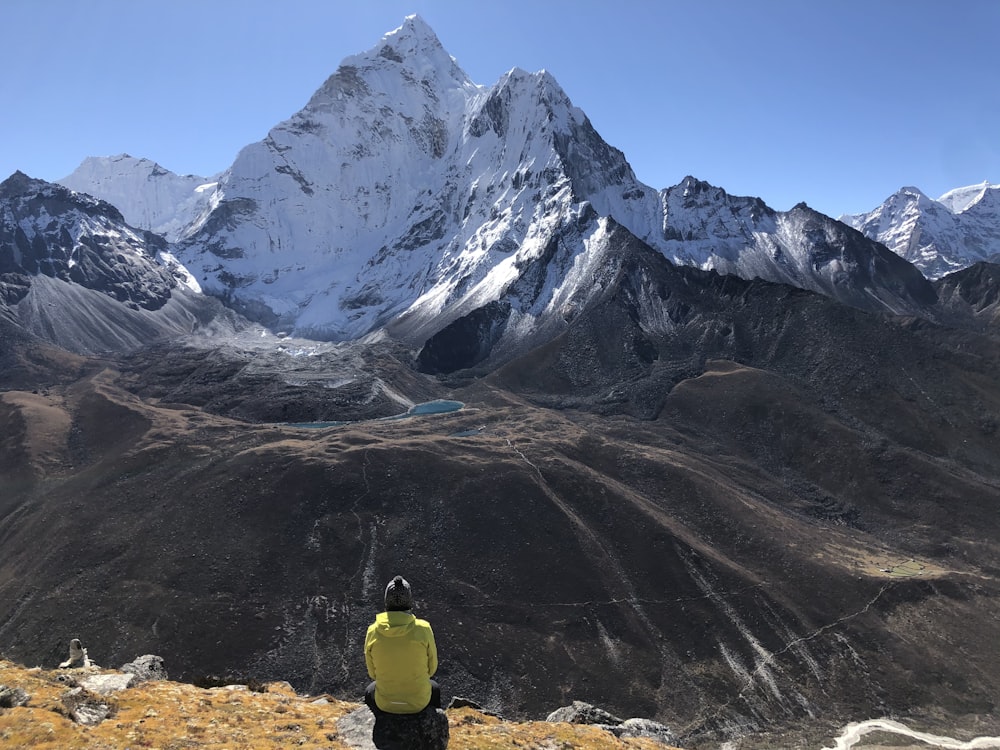 Borsa da trekking gialla e nera sul campo marrone vicino alla montagna grigia e bianca durante il giorno