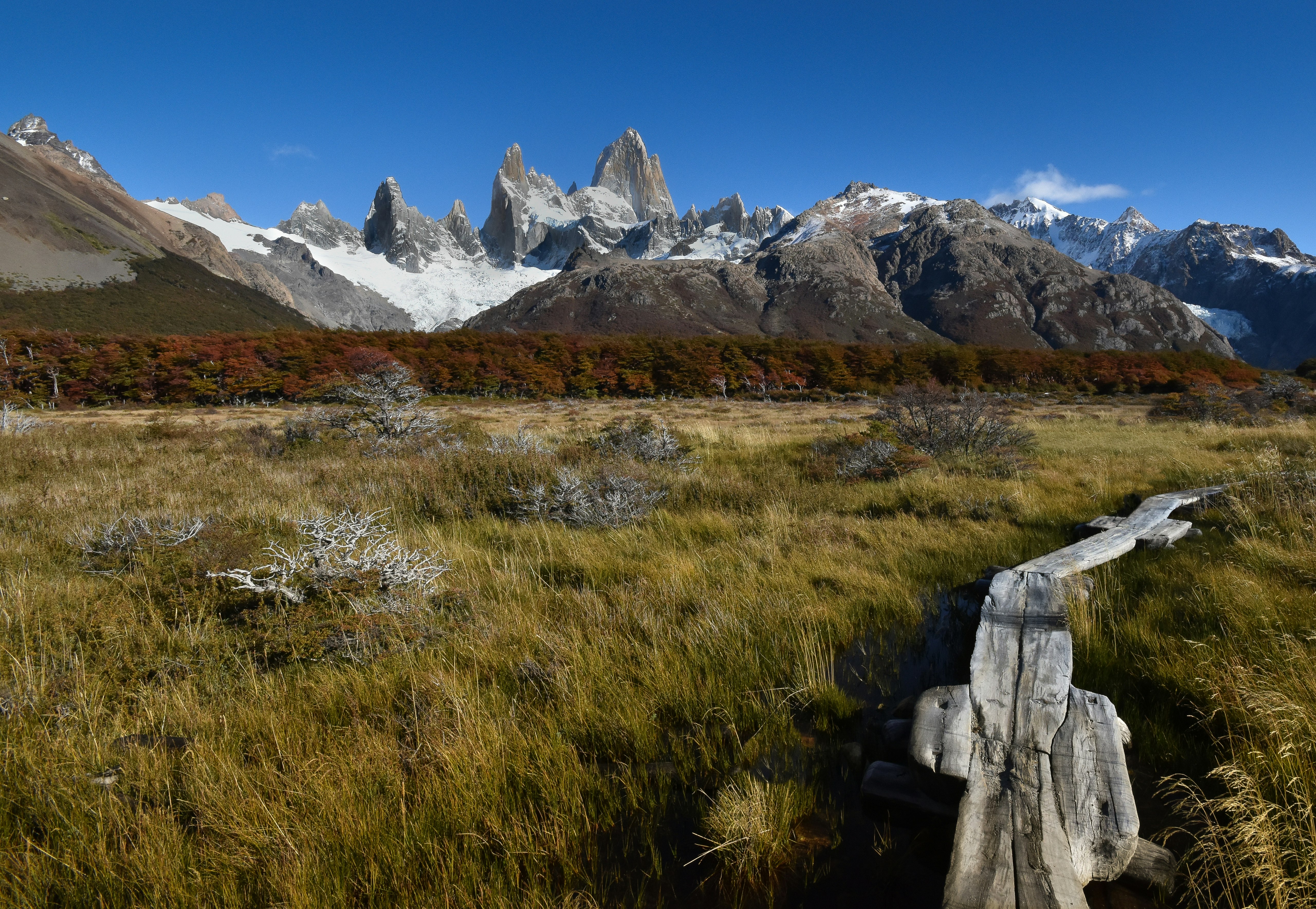 green grass field near mountain under blue sky during daytime