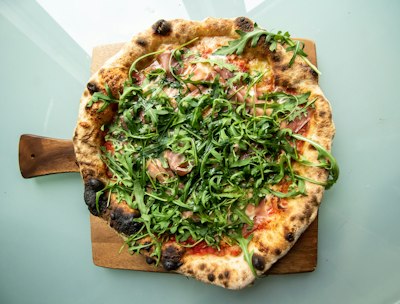 Pizza bianca au prosciutto crudo San Daniele et roquette fraîche sur plateau