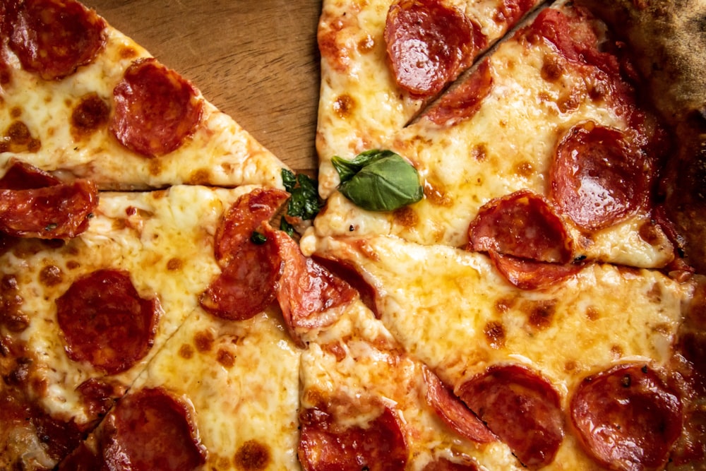 pizza with green leaves on brown wooden table