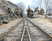 brown metal train rail near rocky mountain during daytime