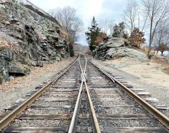 brown metal train rail near rocky mountain during daytime