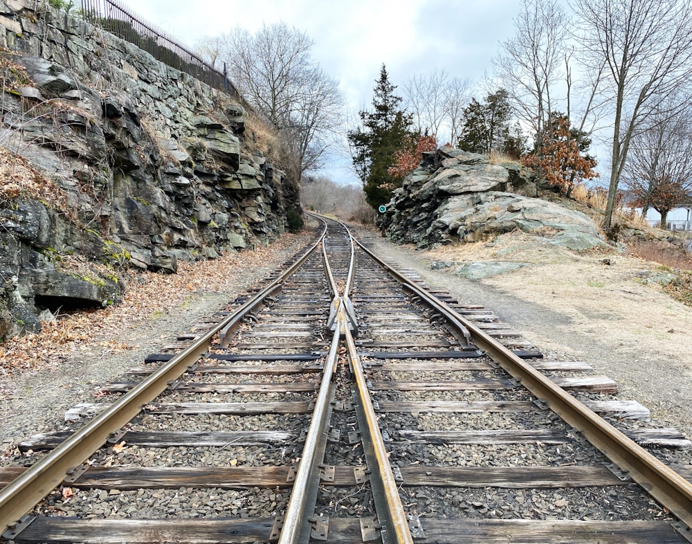 brown metal train rail near rocky mountain during daytime