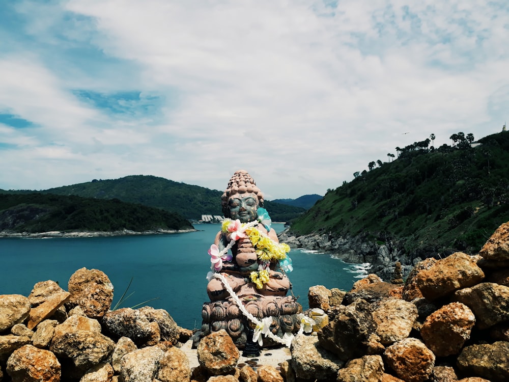 man in green jacket sitting on rock near body of water during daytime