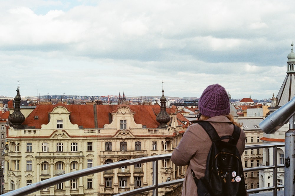 woman in purple knit cap and brown jacket standing near railings